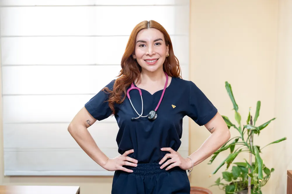 Mariángel con uniforme sanitario azul marino, de pie en su consulta.